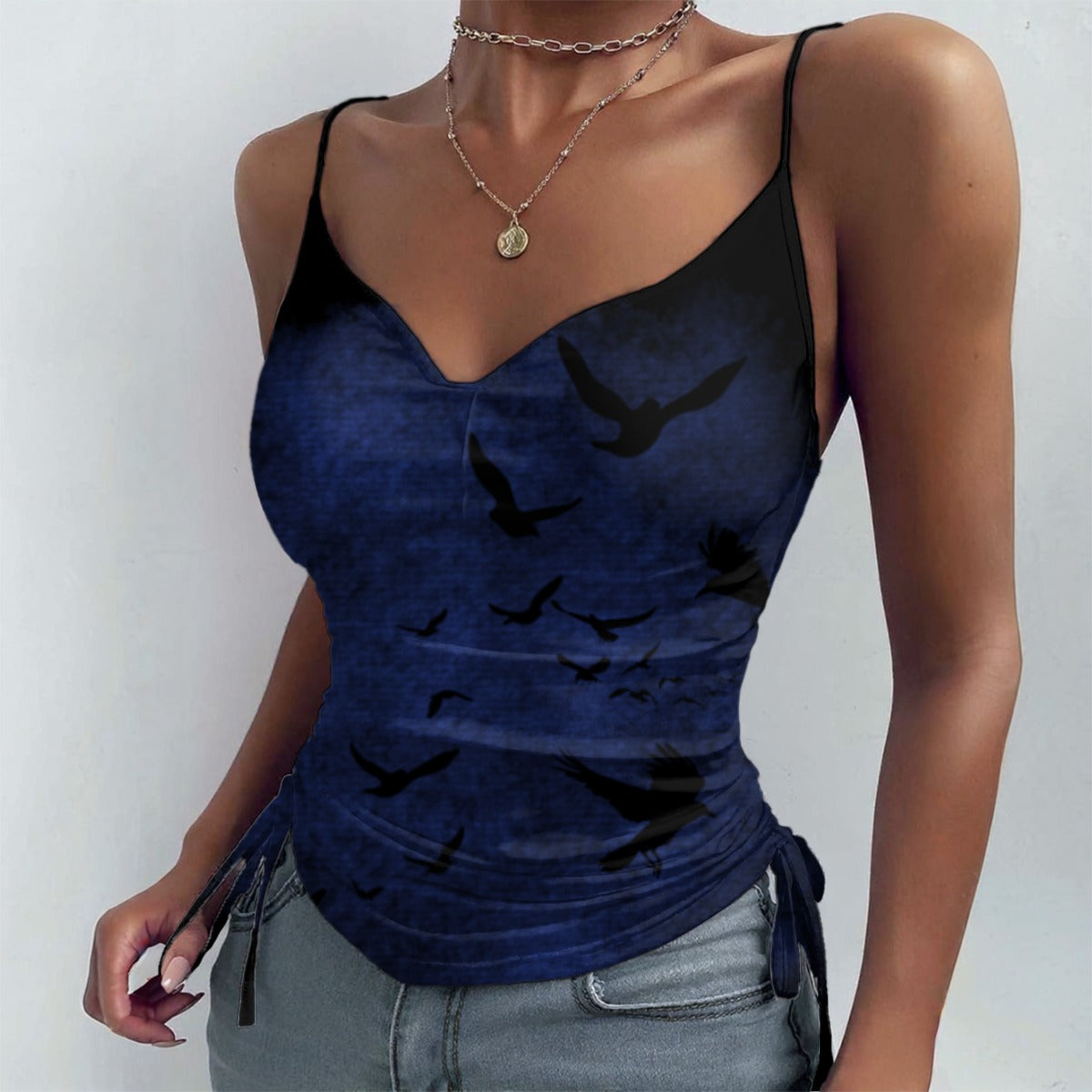 Woman wearing a blue tank top with black bird patterns on a plain background