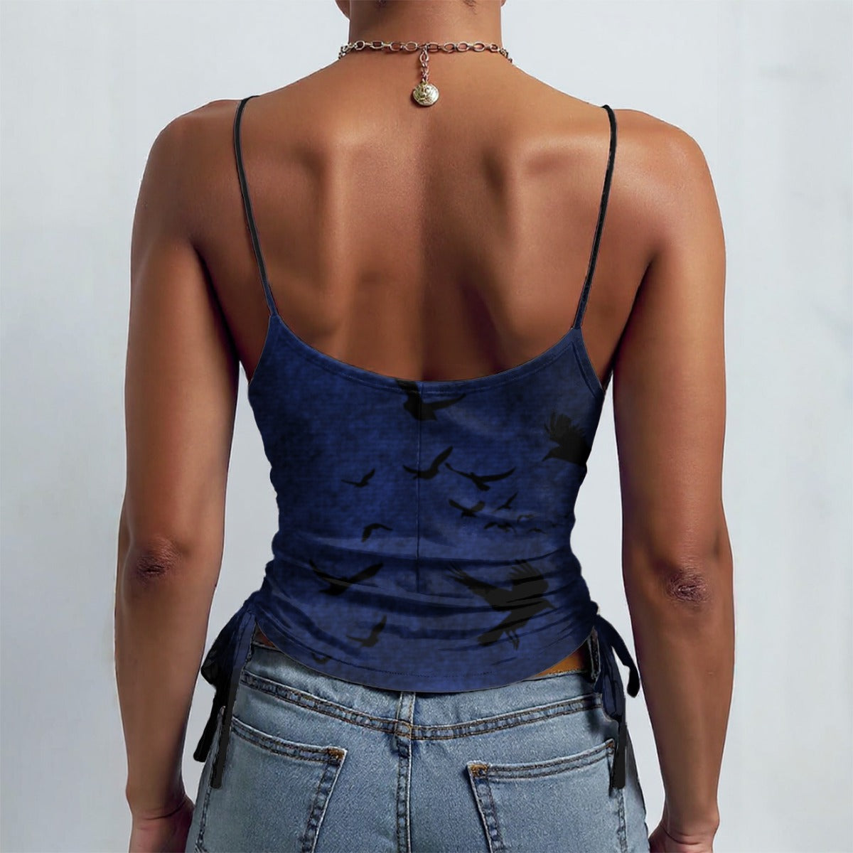 Person wearing a blue tank top with black paint splashes and blue jeans on a plain background