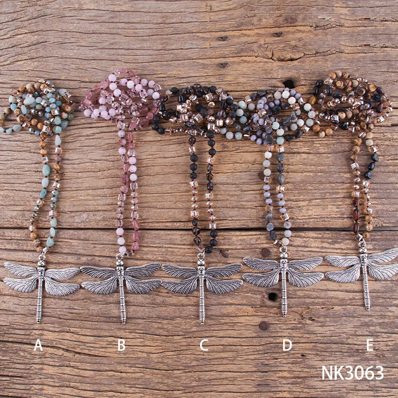 Five beaded necklaces with dragonfly pendants on a wooden surface, labeled A to E and NK3063.