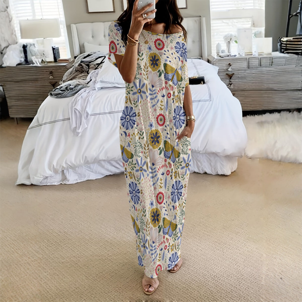 Woman taking a mirror selfie wearing a colorful floral jumpsuit in a bedroom.