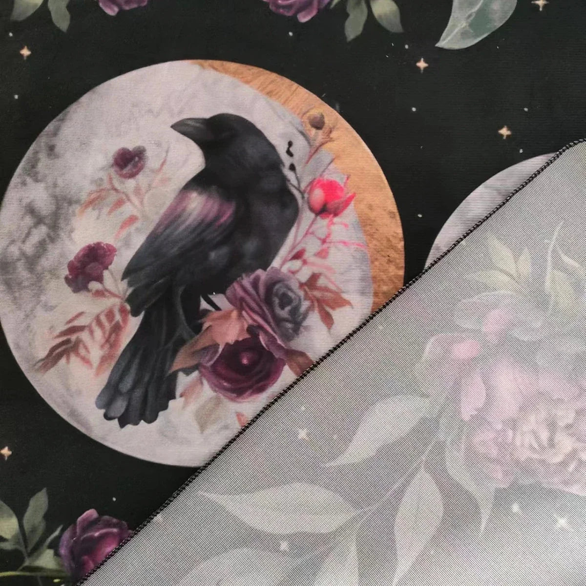 Decorative fabric with a black crow, flowers, and moon design on a dark background.